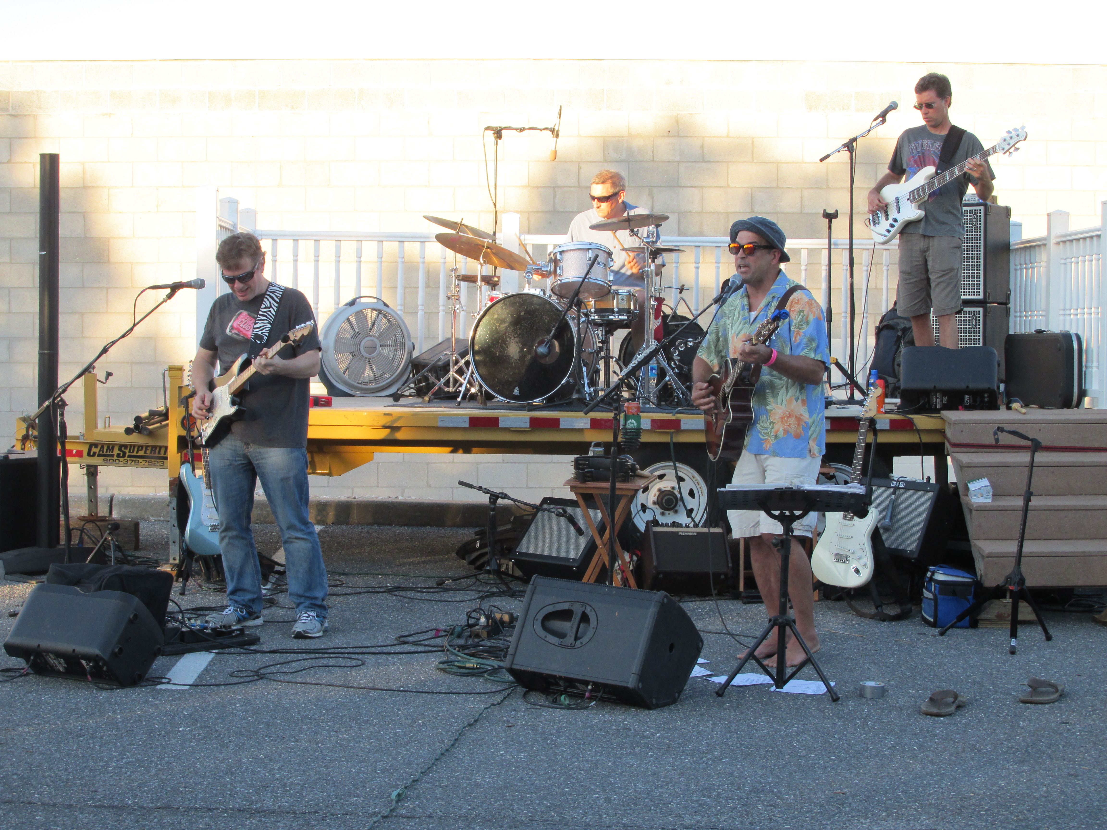 A band performs live outdoors with instruments and microphones.