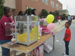Outdoor popcorn stand with people and balloons.