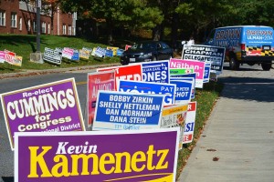 Election campaign signs along a sidewalk.