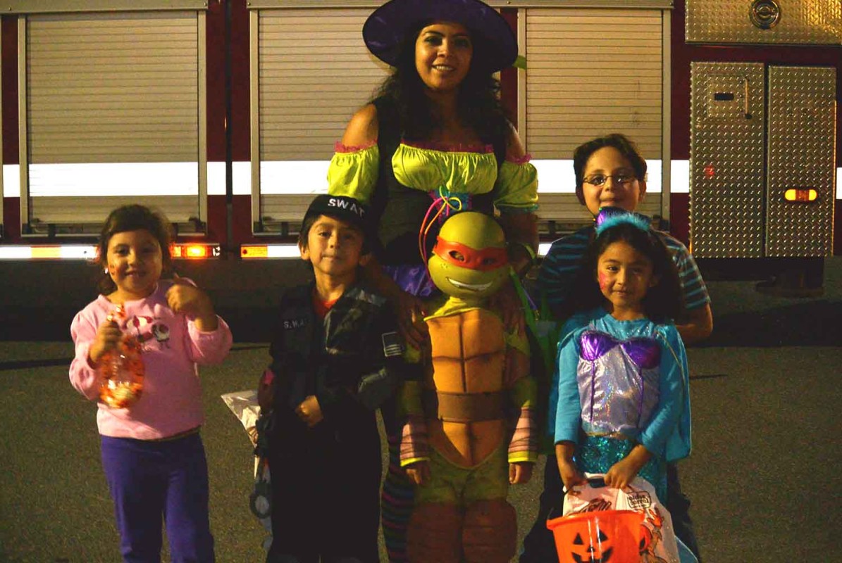 Kids and an adult in Halloween costumes posing outdoors.