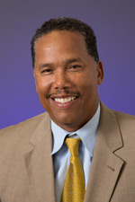 Smiling man in suit and yellow tie.