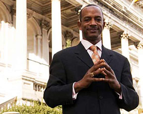 Man in suit standing before large building.