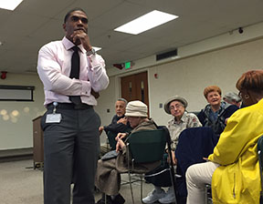 Man speaking thoughtfully to a seated audience in a classroom.