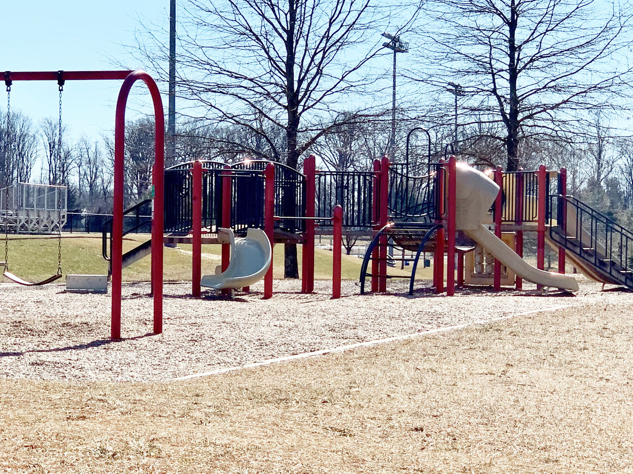 Empty playground with climbing structures and slides on a sunny day.